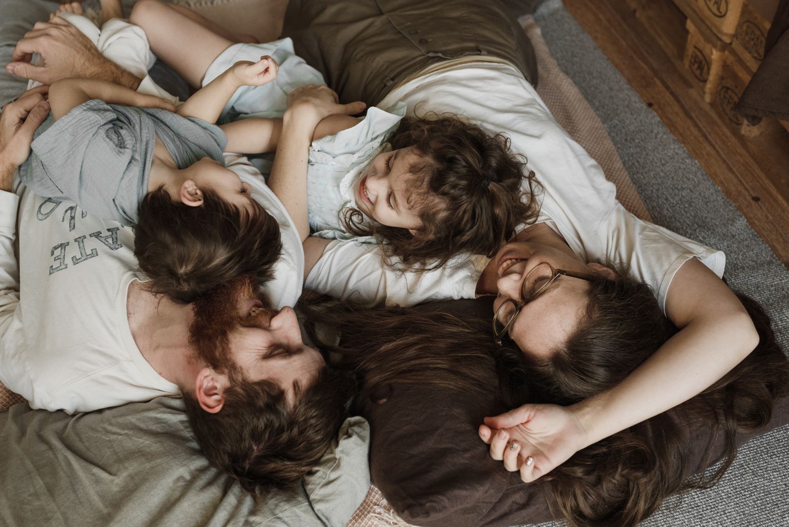 Two parents and their young children cuddling together at home