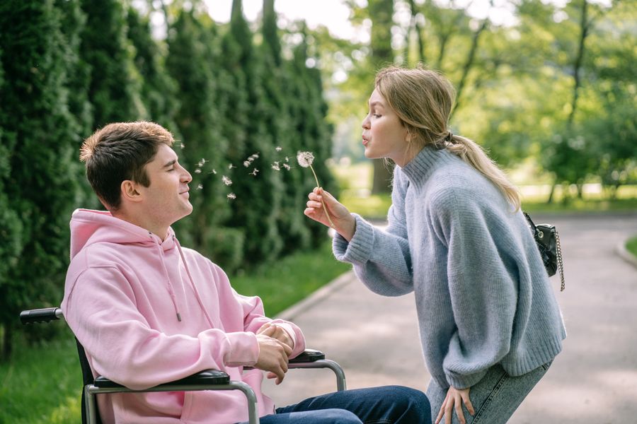 A man using a wheelchair enjoying a sunny day outdoors with his partner